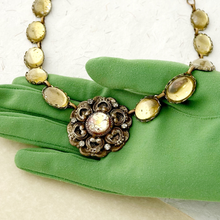 Load image into Gallery viewer, Decorative necklace with gold and bronze elements on a green glove