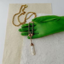 Load image into Gallery viewer, a mother of pearl pendant on gold plated chain displayed on a green gloved hand