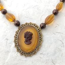 Load image into Gallery viewer, close-up of amber glass cameo and beads on a paper background