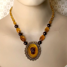 Load image into Gallery viewer, Necklace with amber-colored beads and cameo pendant on a mannequin