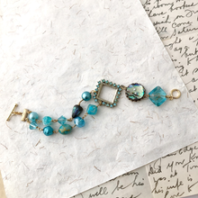 Load image into Gallery viewer, Aqua beaded bracelet on a textured white surface with handwritten text