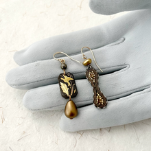 Load image into Gallery viewer, Handmade earrings made with vintage elements in bronze and charcoal tones displayed on a grey gloved hand