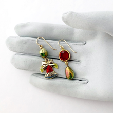 Load image into Gallery viewer, Pair of festive earrings with red and green beads displayed on a grey gloved hand