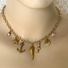 Load image into Gallery viewer, Gold toned charm necklace on a mannequin