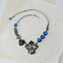 Load image into Gallery viewer, vintage assemblage necklace in blue and silver tones displayed on textured paper background