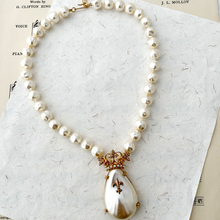 Load image into Gallery viewer, Faux pearl necklace with a large faux pearl pendant with crown on a textured paper background