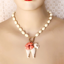Load image into Gallery viewer, mannequin wearing a necklace of cream beads with poodle and coral coloured flower charms