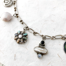 Load image into Gallery viewer, close up of silver, pearl and abalone shell charms on a textured white surface