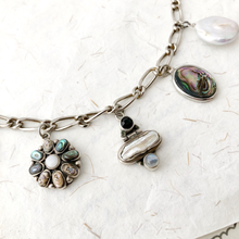 Load image into Gallery viewer, close up of silver, pearl and abalone shell charms on a textured white surface