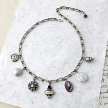 Load image into Gallery viewer, Necklace with various silver, pearl and abalone shell charms on a textured white surface