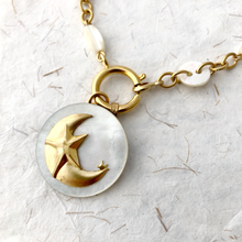 Load image into Gallery viewer, Necklace with a gold crescent moon and mother-of-pearl pendant on a textured white background