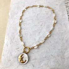 Load image into Gallery viewer, Necklace with a gold crescent moon and mother-of-pearl pendant on a textured white background