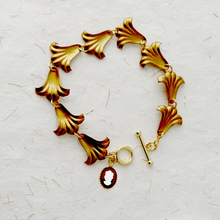 Load image into Gallery viewer, bracelet with flower shaped links and vintage cameo accent displayed on a textured paper background