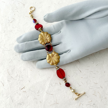 Load image into Gallery viewer, bracelet of red and old vintage components displayed on a grey gloved hand