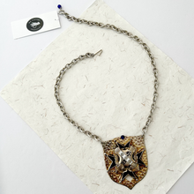 Load image into Gallery viewer, Necklace with decorative pendant on a textured white surface