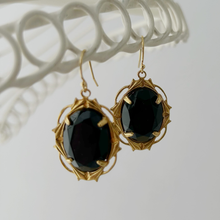 Load image into Gallery viewer, black glass earrings in gold toned frames hanging from a wire frame