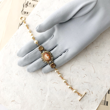 Load image into Gallery viewer, Bracelet with vintage cameo and pearl beads displayed on a gloved hand