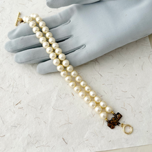 Load image into Gallery viewer, double stranded pearl bracelet displayed on a grey gloved hand on handmade paper background