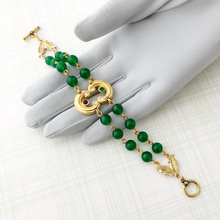 Load image into Gallery viewer, bracelet with gold focal and two strands of emerald Lucite beads displayed on a gloved hand