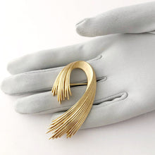 Load image into Gallery viewer, curled wave shaped gold toned vintage brooch displayed on a gloved hand