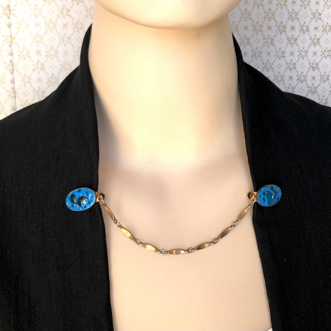 blue enamelled copper sweater clips on a black jacket