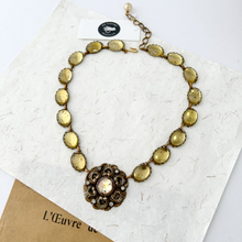 Load image into Gallery viewer, gold and yellow necklace with elaborate focal on mixed paper background
