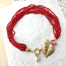 Load image into Gallery viewer, a red necklace with gold leaf and pearl charm against a neutral background
