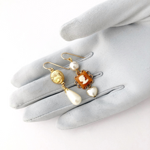 Load image into Gallery viewer, asymmetric earrings with gold filled locket, cameo, vintage pearl beads displayed on a gloved hand
