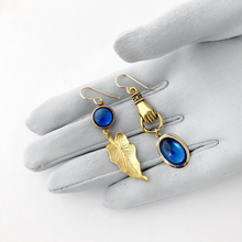 Load image into Gallery viewer, asymmetric earrings in blue and gold displayed on a gloved hand
