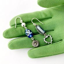 Load image into Gallery viewer, asymmetric earrings in blue and silver isplayed on a green gloved hand
