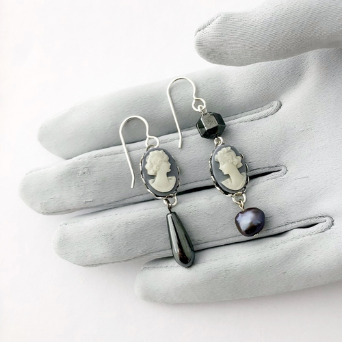 Pair of earrings with vintage cameos and beads on a grey gloved hand