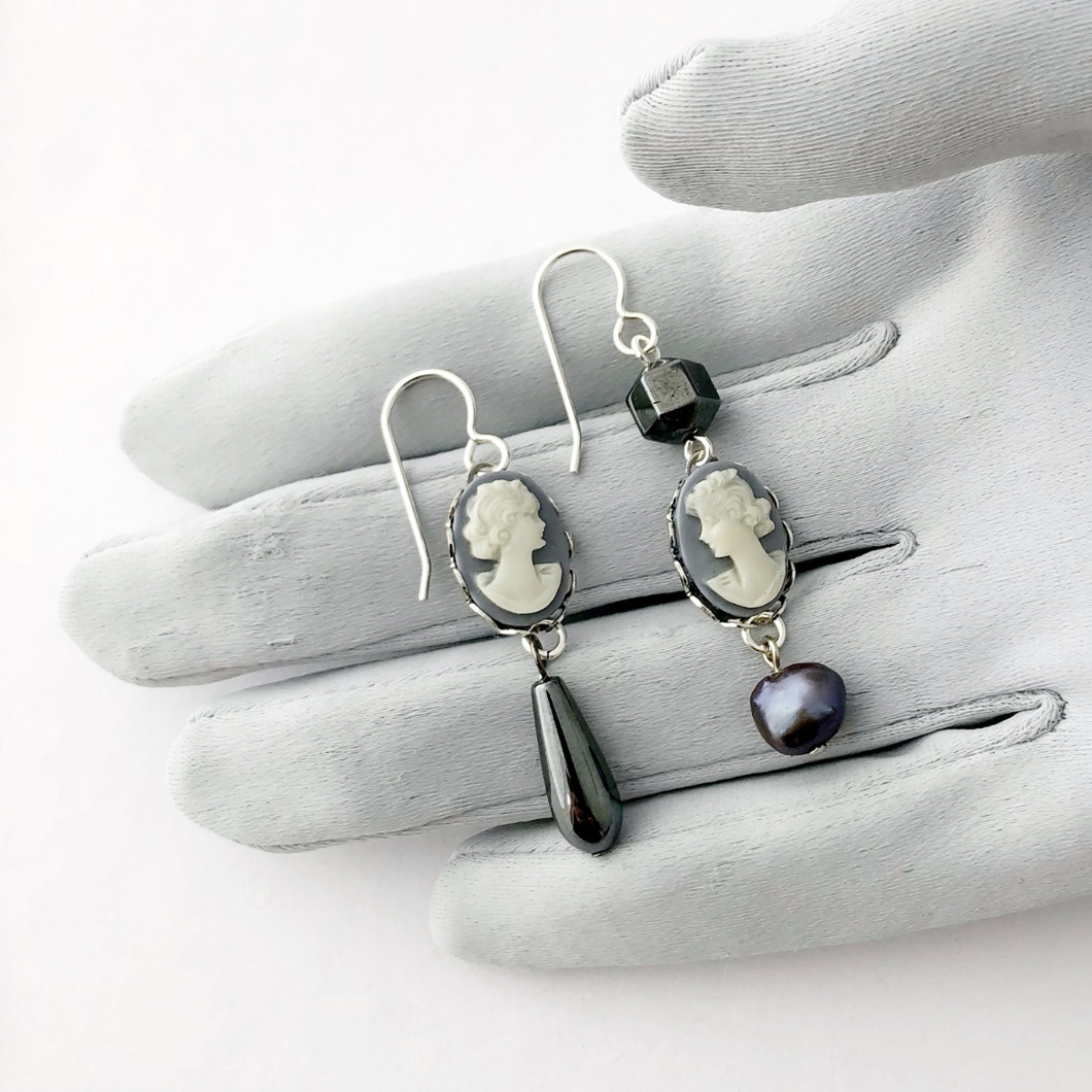 Pair of earrings with vintage cameos and beads on a grey gloved hand
