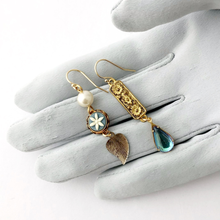 Load image into Gallery viewer, Asymmetric earrings with vintage floral and leaf designs displayed on a gloved hand

