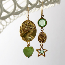 Load image into Gallery viewer, asymmetric earrings with gold metal cameos, green heart shaped rhinestone and star charm hanging from a white frame
