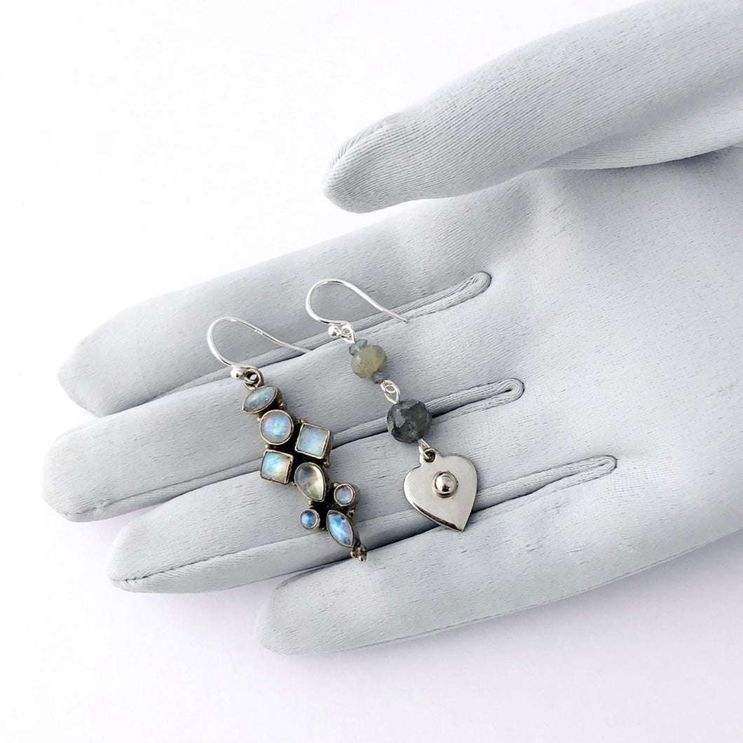 asymmetric earrings in silver and blue colours containing Labradorite and Blue Moonstone displayed on a gloved hand