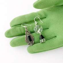 Load image into Gallery viewer, asymmetric earrings with marcasite and sterling silver Art Deco style drop, vintage crystal beads and chandelier crystal displayed on a green gloved hand
