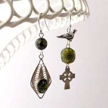 Load image into Gallery viewer, asymmetric earrings in silver and bronze green colours hanging from a white wire lace frame
