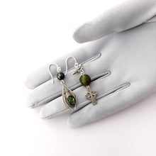 Load image into Gallery viewer, asymmetric earrings in silver and bronze green colours  displayed on a gloved hand
