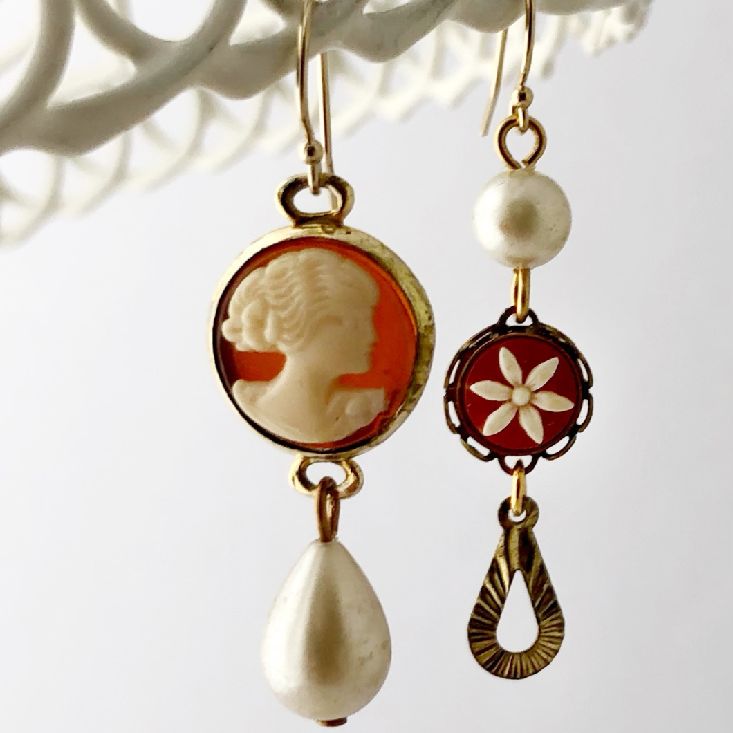 asymmetric vintage cameo earrings with pearls hanging against a white background