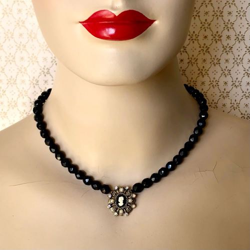 Black beaded necklace with a cameo pendant on a mannequin with red lips.