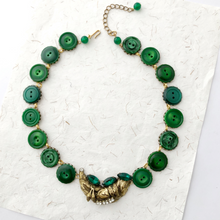 Load image into Gallery viewer, statement necklace in antique gold with emerald green buttons displayed flat

