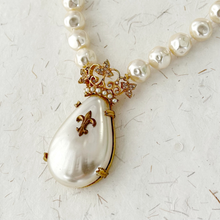 Load image into Gallery viewer, close-up of necklace with a large faux pearl pendant with crown on a textured paper background
