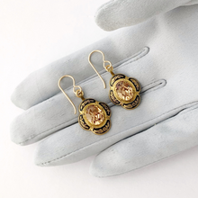 Load image into Gallery viewer, black and gold earrings with light topaz rhinestone centres on a gloved hand
