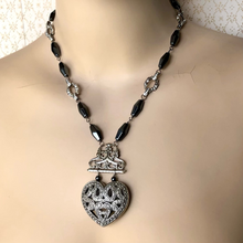 Load image into Gallery viewer, statement necklace in hematite and silver tones with large heart focal displayed on a mannequin
