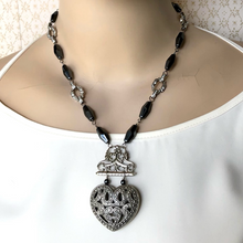 Load image into Gallery viewer, statement necklace in hematite and silver tones with large heart focal displayed on a mannequin with white top
