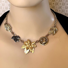 Load image into Gallery viewer, Necklace made with vintage metal leaves and a squirrel charm on a mannequin against a patterned background
