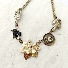 Load image into Gallery viewer, Necklace made with vintage metal leaves and a squirrel charm on a handmade paper background
