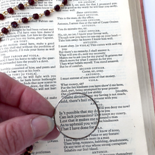 Load image into Gallery viewer, hand holding a lens over a vintage book with garnet glass beads in the background
