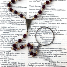 Load image into Gallery viewer, Y-shaped necklace with lens and garnet glass beads on a vintage book
