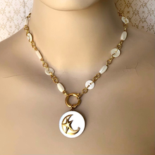 Load image into Gallery viewer, Necklace with a gold crescent moon and mother-of-pearl pendant on a mannequin against a patterned background
